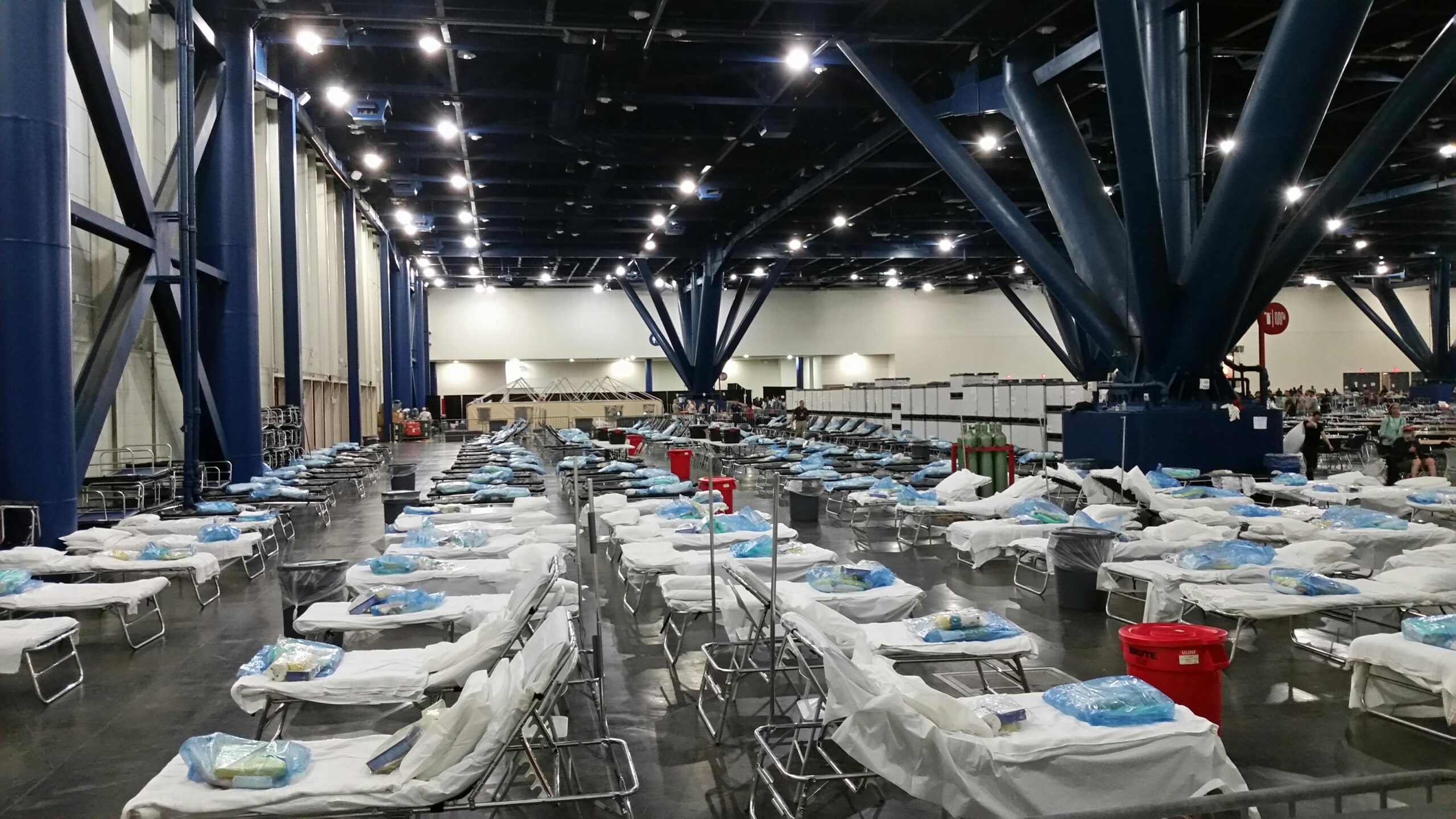 Large indoor temporary medical station with rows of prepared hospital beds and supplies.